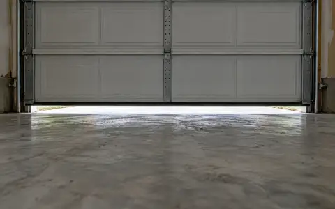 A garage door stopped a few inches above the floor, daylight showing under it